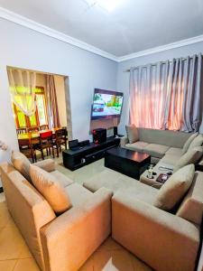 Una sala de estar con un sofá y un televisor de pantalla plana. en Karibu Jua Backpackers Hostel, en Mbeya