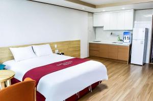 sypialnia z dużym białym łóżkiem i kuchnią w obiekcie Jeju Sunbeach Hotel & Resort w mieście Czedżu