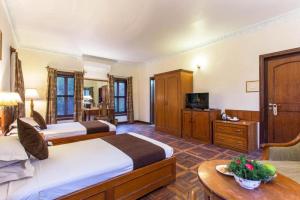 a hotel room with two beds and a television at Godavari Village Resort in Kathmandu