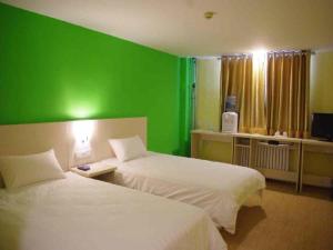two beds in a room with a green wall at Jinghua Hotel Xingtai Train Station in Xingtai