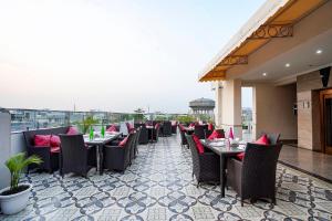 a restaurant with tables and chairs on a balcony at FabHotel Divine & Banquet in Noida