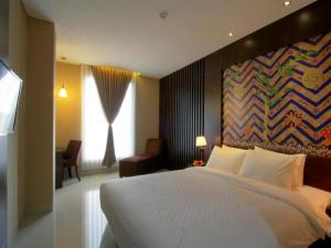 a bedroom with a white bed and a painting on the wall at Hotel Betha Subang in Bandung