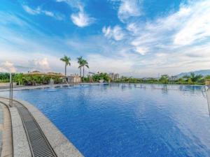 a large swimming pool with blue water and palm trees at Great International Hotel in Heyuan