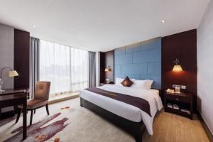 a hotel room with a large bed and a desk at Foshan Xin Hu Hotel in Foshan +207 photos