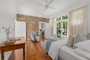 a white bedroom with a bed and a table at Studio Cottage Alpine Southern Highlands in Alpine