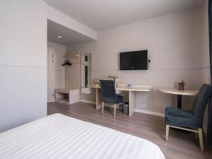 una stanza con un letto, un tavolo e delle sedie di Jinjiang Inn Wuxi Li Lake Yauntouzhu Scenic Spot a Wuxi