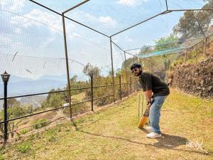 a man holding a baseball bat in front of a fence at Winterline Gold Resort in Lansdowne