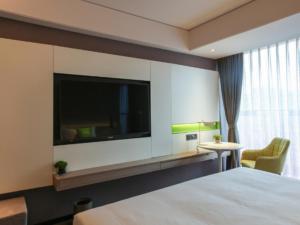 a hotel room with a bed and a flat screen tv at ibis Styles Yangzhou Baixiang Rd Hotel in Yangzhou