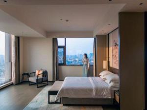 a woman standing in a bedroom with a large bed at Dajiuhua Hotel in Chizhou +279 photos