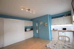 une cuisine avec des armoires blanches et un mur bleu dans l'établissement Appartement avec piscine et accès direct à la mer, à Châtelaillon-Plage 3 autres photos