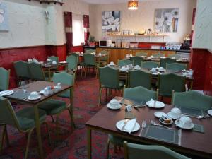 ein Esszimmer mit Tischen und grünen Stühlen in der Unterkunft Hilbre Hotel in Blackpool