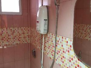 une douche dans une salle de bain avec un sèche-cheveux au mur dans l'établissement OYO 75352 Hotel Family House And Resort Phetchaburi, à Ban Lahan Bon