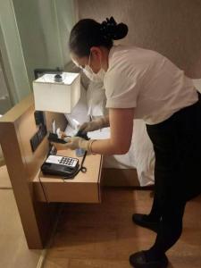 a woman standing next to a desk with a telephone at V8 Ziyuangang Hotel in Guangzhou