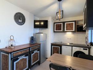 a kitchen with a refrigerator and a table in it at Le 72ème flocon, T2, vue imprenable, résidence calme, 100 m des pistes in Le Dévoluy +6 photos