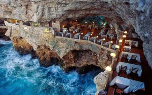 a restaurant on a cliff next to a body of water at Casa Aurora in Polignano a Mare