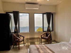 a bedroom with two chairs and a bed and windows at Winterline Gold Resort in Lansdowne