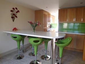 uma cozinha com uma mesa branca e bancos verdes em Maple Cottage B&B em Gullane