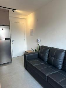 a black leather couch in a living room with a refrigerator at Apto Completo, 3min Estação Higienópolis Mackenzie Consolação in Sao Paulo