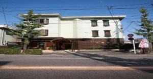 a white building on the corner of a street at Business Hotel Wako in Ichinomiya