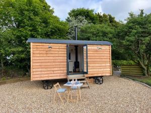 a small wooden shed with a table and chairs at Kilden Hut - Perranwell Station in Perranwell