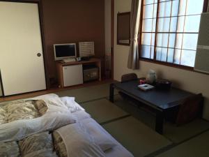 a bedroom with a bed and a table and a tv at Hotel Kikuya in Hakodate