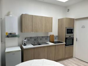 a kitchen with wooden cabinets and a white refrigerator at Appartement rénové, RDC, proche commodités in Armentières