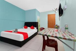 un dormitorio con una cama y una mesa en OYO 90873 Travellers Inn, en Kampong Kijang