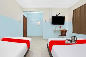 Una habitación de hotel con dos camas y un televisor. en OYO 90873 Travellers Inn, en Kampong Kijang