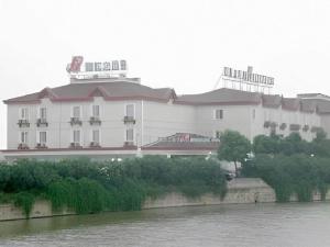 ein großes weißes Gebäude neben einem Fluss in der Unterkunft Magnotel Business Yixing Passenger Station Tuanjiu Scenic Area in Yixing