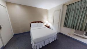 a bedroom with a white bed and a window at Adriatico Arms Hotel in Manila +62 photos