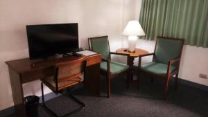 a hotel room with a desk with chairs and a television at Adriatico Arms Hotel in Manila