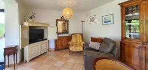 Una sala de estar con un sofá y un televisor. en Maison Josephine, en Kervoz