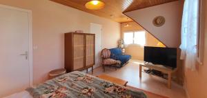 Una sala de estar con una cama y un televisor. en Maison Josephine, en Kervoz