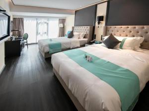 a hotel room with two beds and a television at Xana Hotelle Zhuhai Gongbei Port in Zhuhai