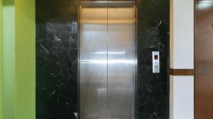 a metal elevator in a room with black tiles at RedDoorz @ Express Inn Lapu Lapu in Gun-ob
