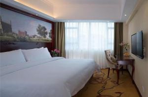 a hotel room with a large bed and a window at Vienna Hotel Shenzhen Pinghu Shuangyong Street Metro Station in Tiantangwei
