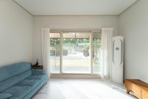 a living room with a blue couch and a sliding glass door at Chuncheon Soopsog Jageun Jib Pension in Chuncheon +8 photos