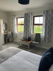 a bedroom with a bed and a desk and two windows at Altarichard Lodge in Armoy