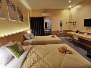 ein Hotelzimmer mit zwei Betten und einem Schreibtisch in der Unterkunft Kiatwimon Hotel in Sathani Phitsanulok
