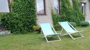 two beach chairs sitting in the grass in front of a house at u Bozeny pokoje in Dźwirzyno