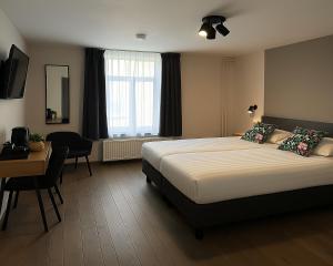 ファルケンブルグにあるHotel Hendrickxのベッドとテーブルと机があるホテルの部屋