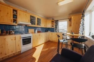 a kitchen with wooden cabinets and a table and chairs at Hamnøy Horizon Lodge in Moskenes +33 photos