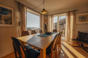 a dining room table with chairs and a large window at Hamnøy Horizon Lodge in Moskenes