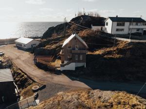 a house on a hill next to the ocean at Hamnøy Horizon Lodge in Moskenes
