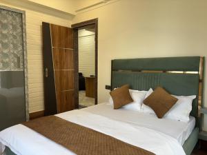 a bedroom with a bed with white sheets and brown pillows at Rishikesh Comfy Stays in Jāmb