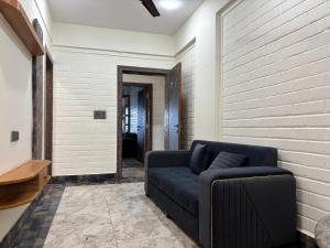 a living room with a blue couch and a brick wall at Rishikesh Comfy Stays in Jāmb