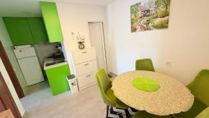 a dining room with a table and green chairs at MANONI APARTMANI in Kumbor