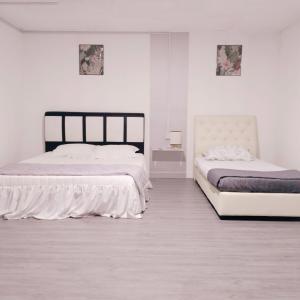 two beds in a white room with white walls at D'boss Homestay Sandakan in Sandakan