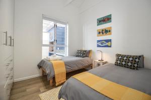 a bedroom with two beds and a window at Cozy Holiday Cottage - XX Cottage Yzerfontein in Yzerfontein