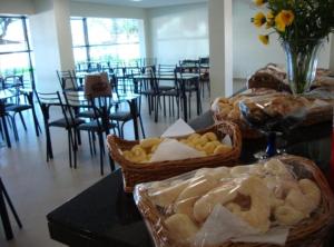 a table with baskets of bread and a room with chairs at HC Hotel Paraopeba in Paraopeba
